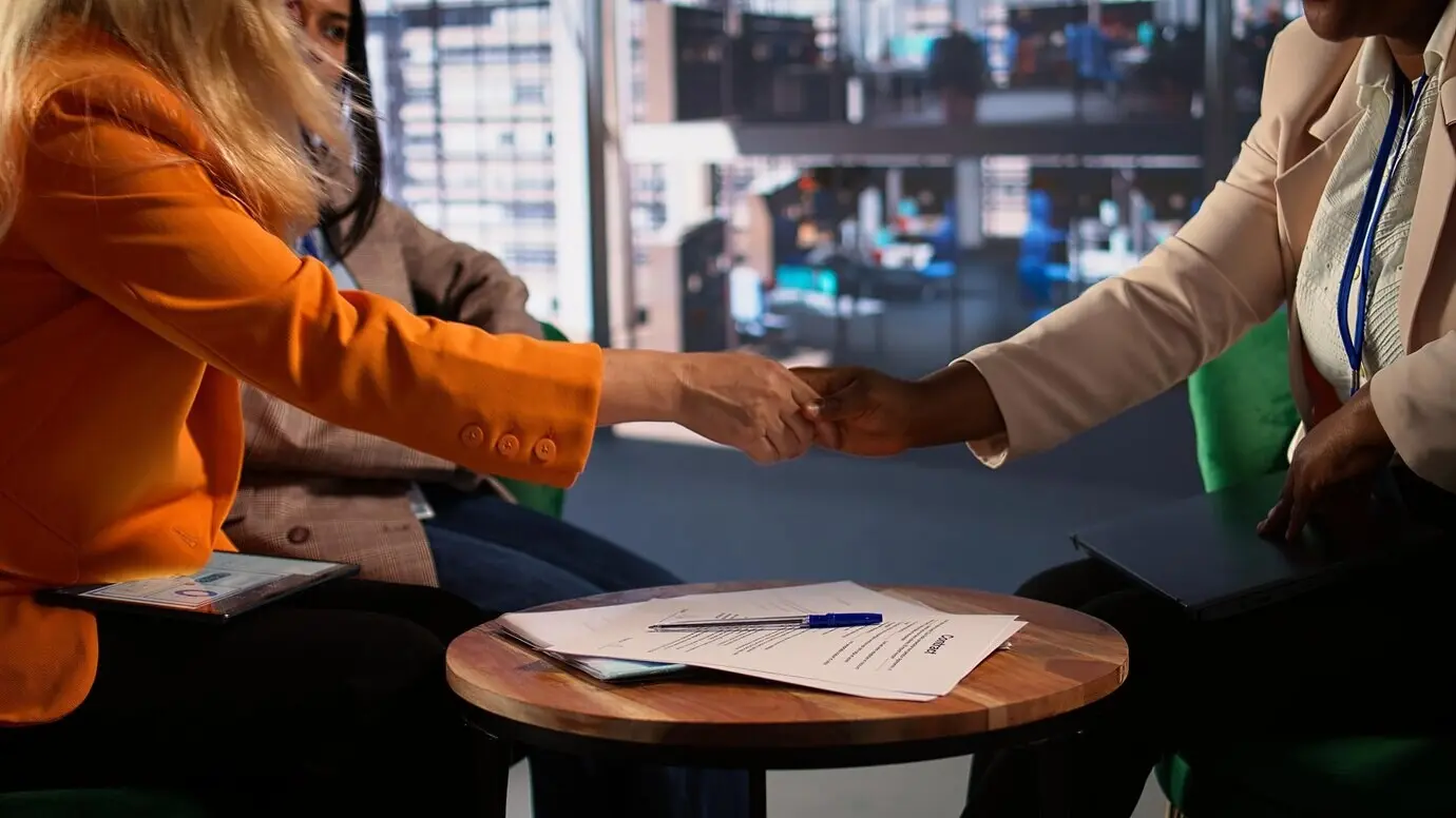 Женщины-предпринимательницы завершают деловую сделку, подписывая документы.