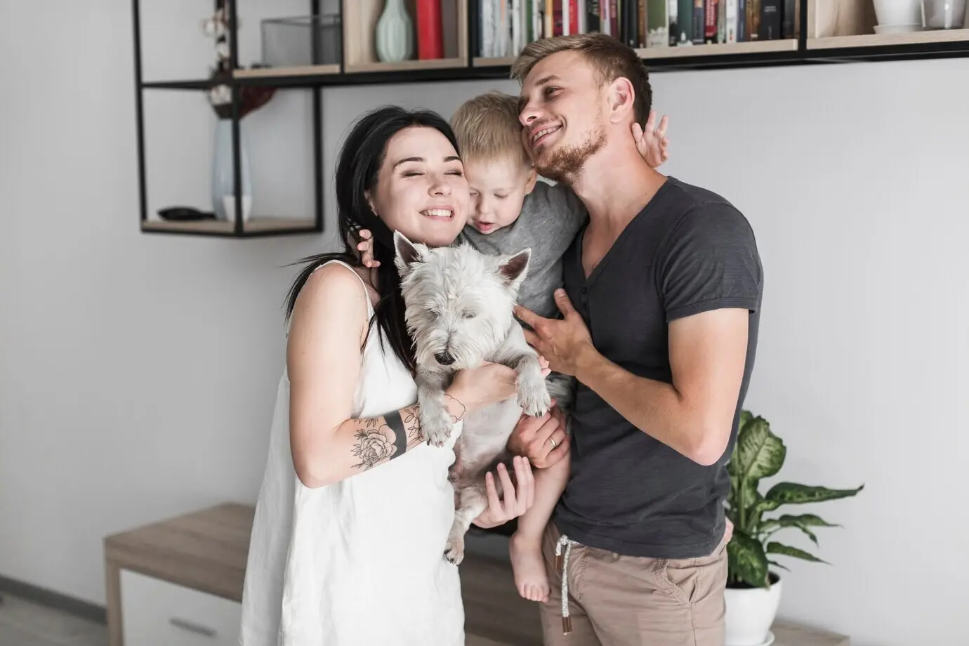 Любящая молодая пара дома со своим милым сыном и белой собакой.